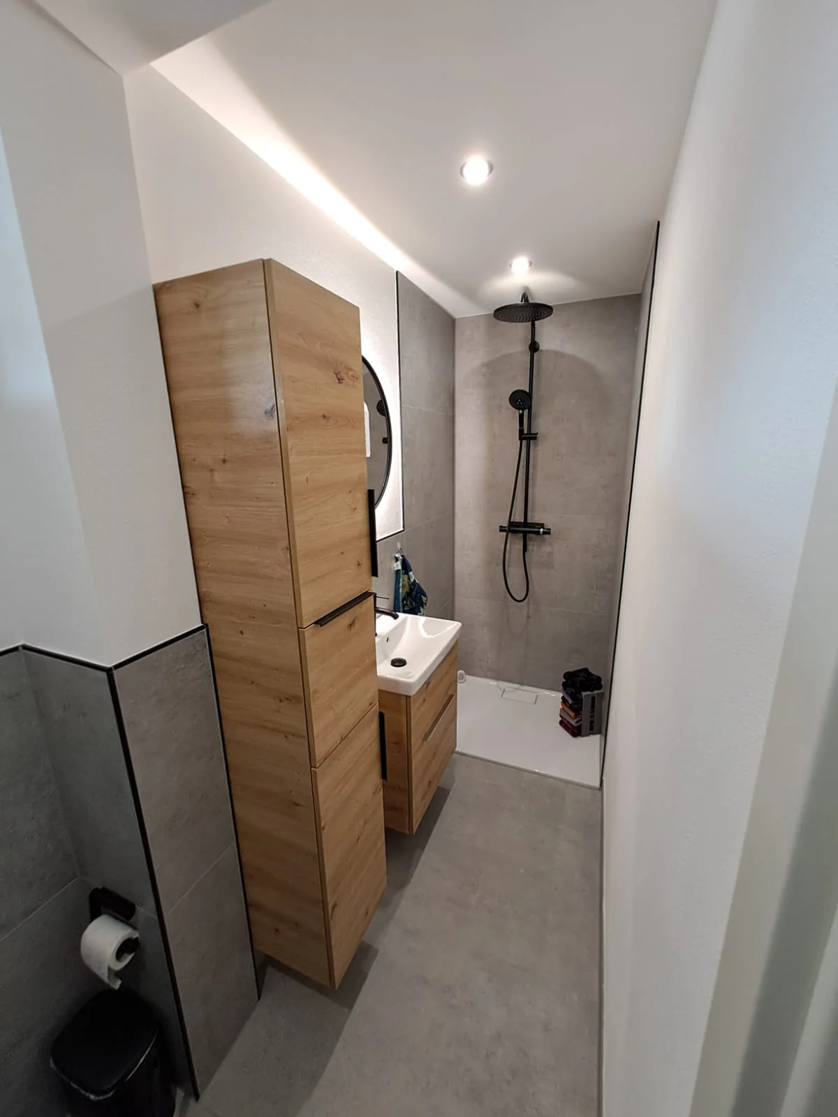 Modernisiertes Bad in Grau, Schwarz und Holz